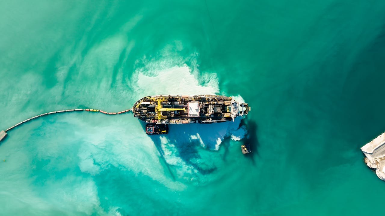 Aerial shot of an industrial ship on turquoise waters with vibrant patterns.